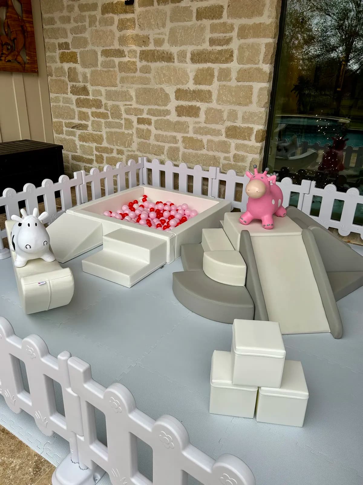 Pink and red ball pit with an elephant rocker on a stone patio