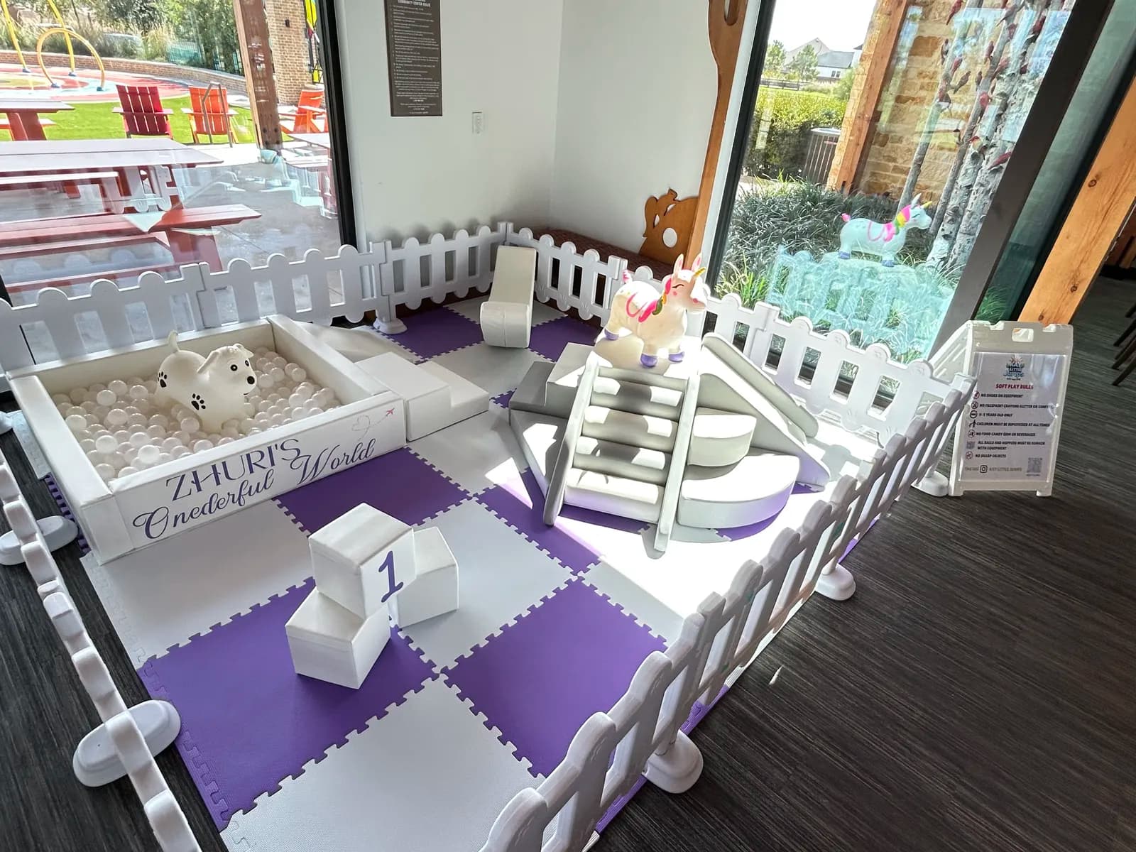 Purple and white soft play setup on a covered patio with a custom name sign