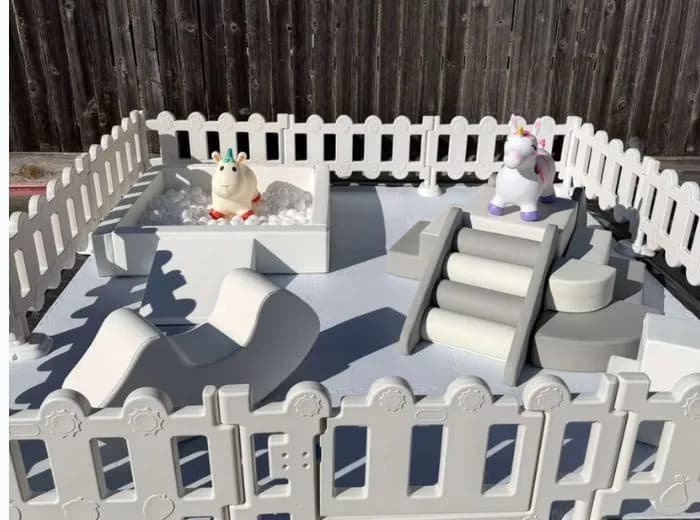 Soft play set with steps, slide, and unicorn figures inside a soft fence